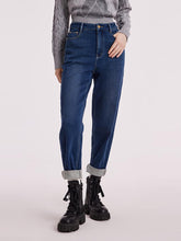 A lady wears a sweater and jeans.